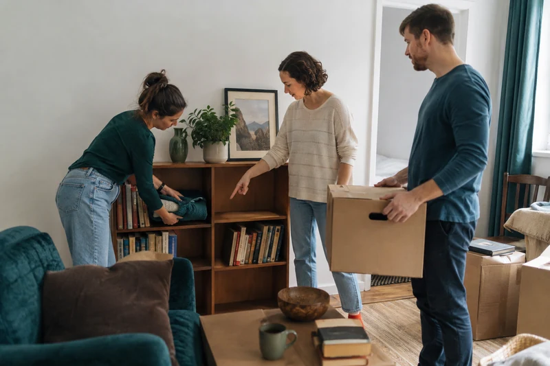 Friends helping arrange belongings in a modest apartment