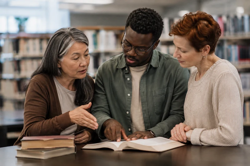 Three friends comparing a source and listening to a question in a library