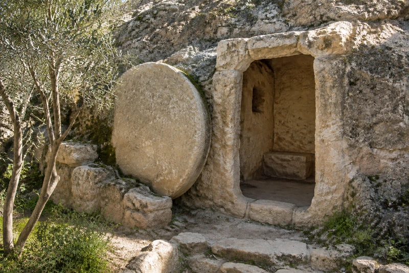 Interpretive illustration of an open empty rock-cut tomb in a garden